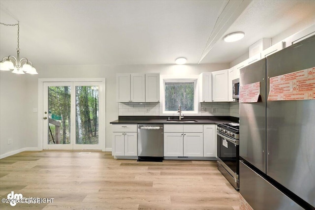 2411 N Friar Tuck Ct, Big Lake, AK 99623 - kitchen with appliances with stainless steel finishes, a sink, dark countertops, decorative backsplash, and a chandelier