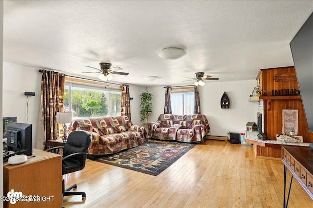 living room with ceiling fan, healthy amount of natural light, light wood finished floors, and a textured ceiling