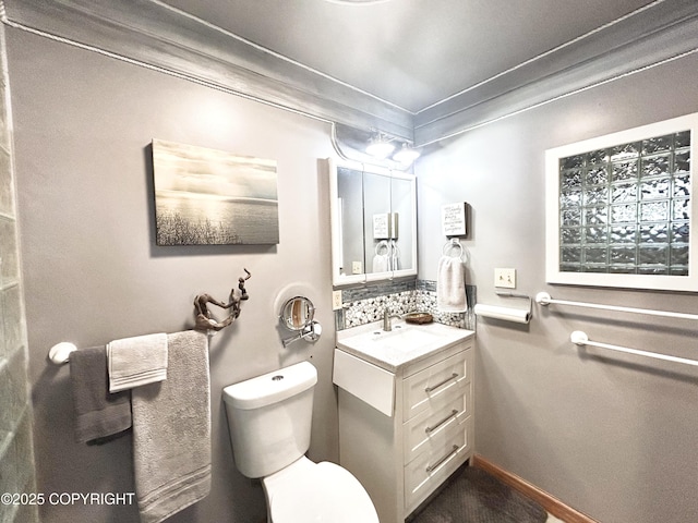 bathroom featuring toilet, vanity, and ornamental molding