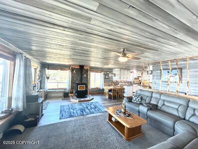 living area featuring a wood stove and a ceiling fan