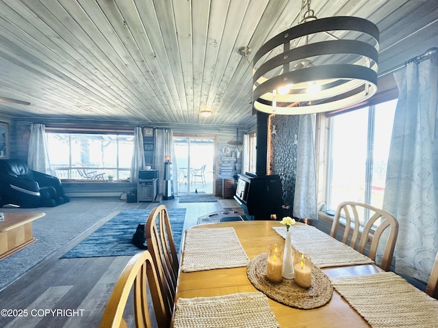 dining area featuring wood finished floors, a wood stove, and wood ceiling