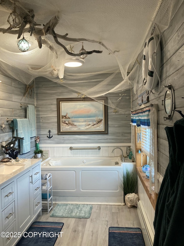 bathroom featuring wooden walls, a baseboard radiator, a garden tub, wood finished floors, and vanity