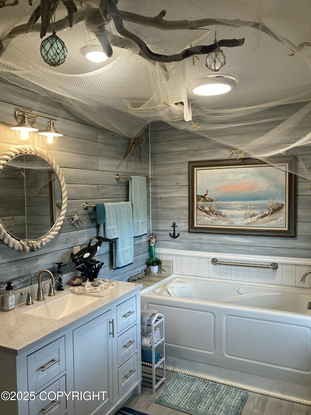 bathroom featuring vanity, a bath, wooden walls, and wood finished floors