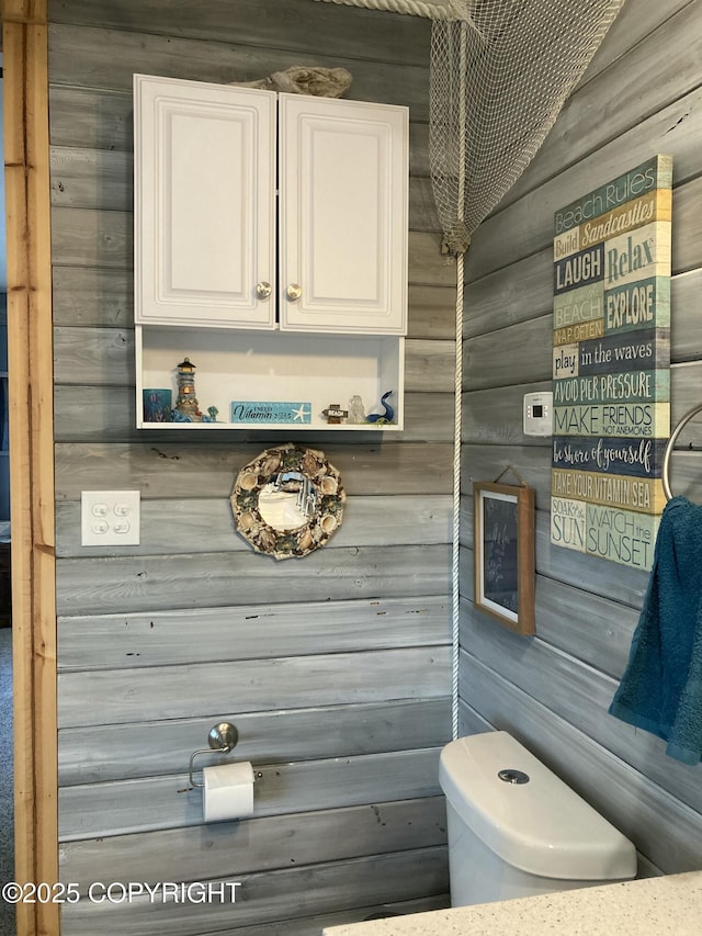 bathroom with wooden walls and toilet