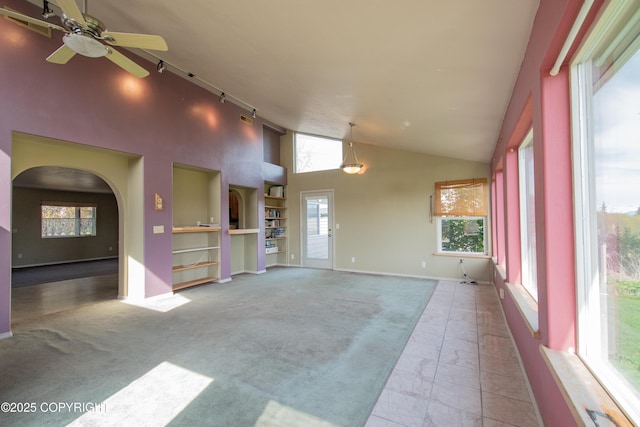 255 Lee Dr, Homer, AK 99603 - unfurnished living room featuring plenty of natural light, built in features, a ceiling fan, high vaulted ceiling, and carpet floors