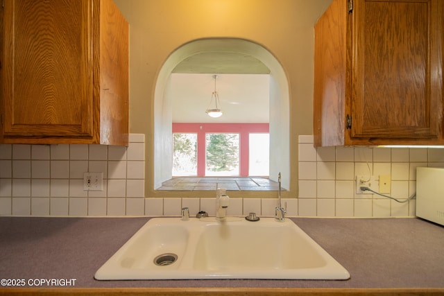 255 Lee Dr, Homer, AK 99603 - kitchen with brown cabinets, a sink, arched walkways, and tasteful backsplash