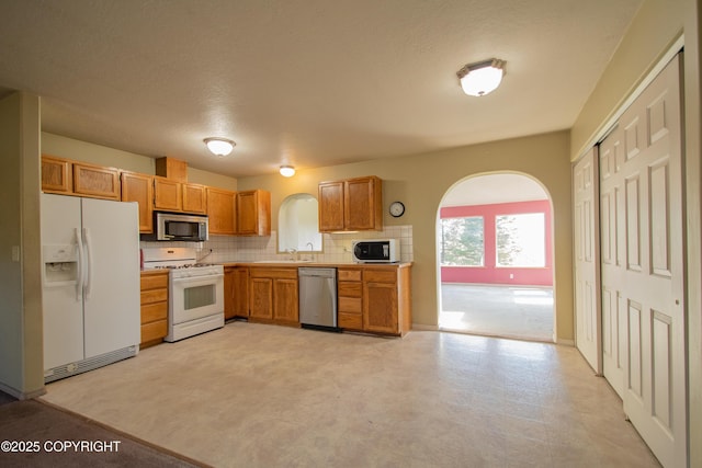255 Lee Dr, Homer, AK 99603 - kitchen featuring stainless steel appliances, backsplash, a sink, light countertops, and brown cabinets
