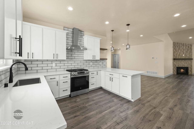 7254 E Riparian Loop, Palmer, AK 99645 - kitchen with stainless steel gas range oven, wall chimney exhaust hood, a sink, a peninsula, and open floor plan