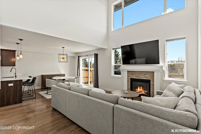 7863 Gate Creek Dr, Anchorage, AK 99502 - living room with dark wood-type flooring, a glass covered fireplace, plenty of natural light, baseboards, and a towering ceiling