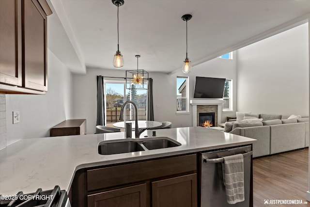 7863 Gate Creek Dr, Anchorage, AK 99502 - kitchen with a sink, stainless steel dishwasher, a fireplace, light stone counters, and pendant lighting