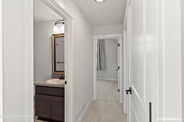 7863 Gate Creek Dr, Anchorage, AK 99502 - hallway with a sink, light colored carpet, and baseboards