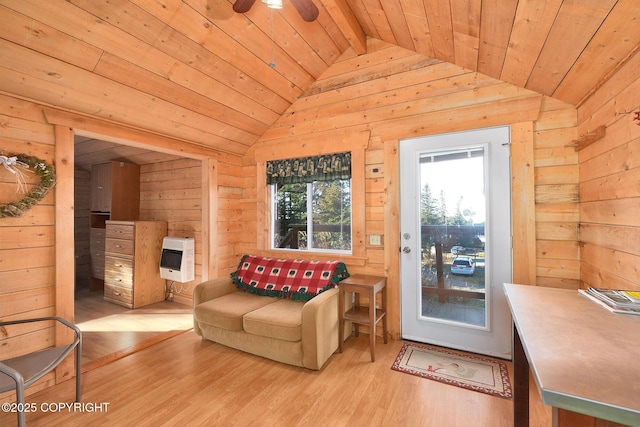 living area with wood walls, wood ceiling, vaulted ceiling, heating unit, and wood finished floors