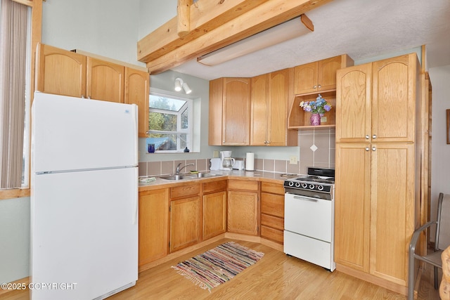 kitchen with white appliances, a sink, light wood-type flooring, and light countertops