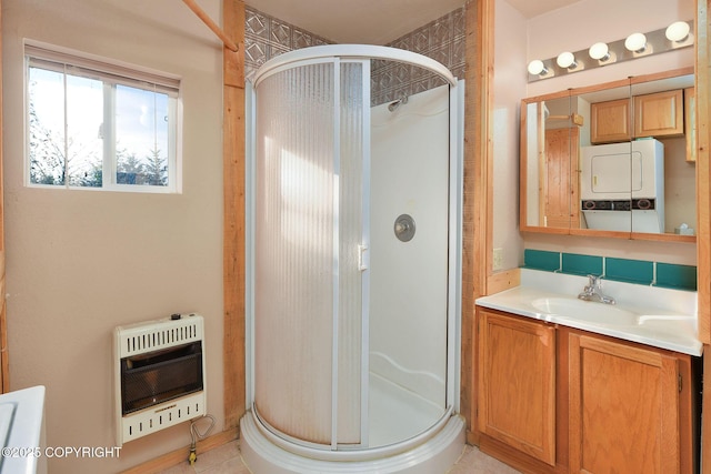 full bath with heating unit, stacked washing machine and dryer, a stall shower, vanity, and tile patterned flooring