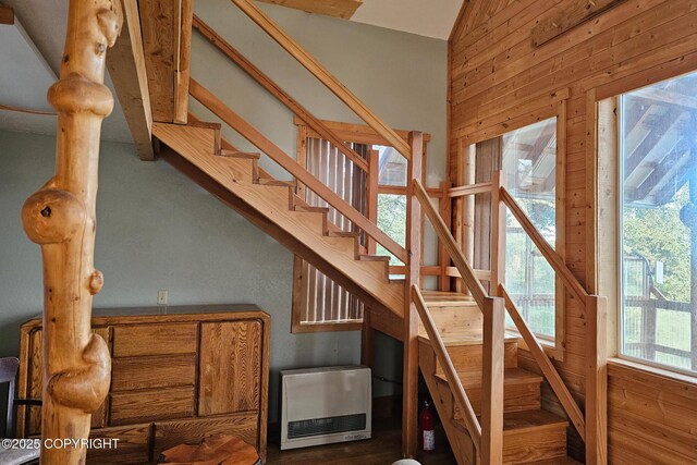 stairs with heating unit, wooden walls, and vaulted ceiling