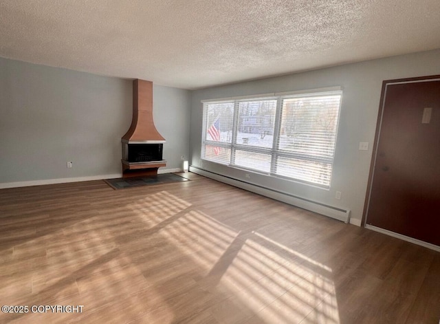 933 W 20th Ave, Anchorage, AK 99503 - unfurnished living room featuring a textured ceiling, a baseboard radiator, a wood stove, and wood finished floors