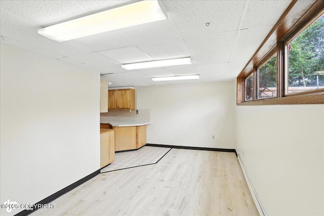 933 W 20th Ave, Anchorage, AK 99503 - unfurnished room featuring light wood-style floors, a drop ceiling, and a baseboard heating unit