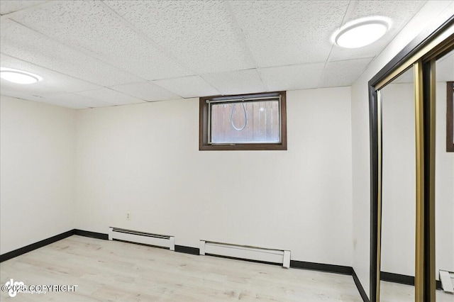 933 W 20th Ave, Anchorage, AK 99503 - below grade area with wood finished floors, a baseboard heating unit, and a drop ceiling