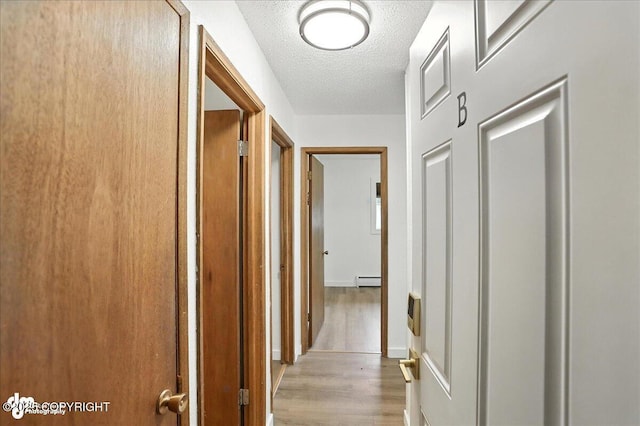 933 W 20th Ave, Anchorage, AK 99503 - hallway featuring wood finished floors, a textured ceiling, and baseboard heating