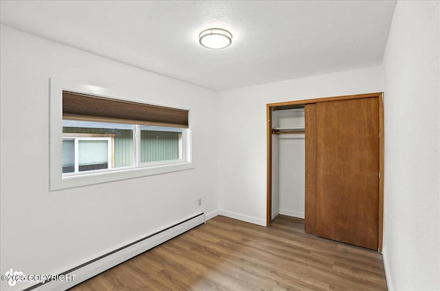 933 W 20th Ave, Anchorage, AK 99503 - unfurnished bedroom with baseboard heating, wood finished floors, and a closet