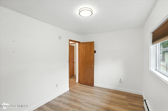 933 W 20th Ave, Anchorage, AK 99503 - unfurnished room with light wood-style floors and a baseboard radiator