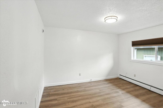 933 W 20th Ave, Anchorage, AK 99503 - unfurnished room featuring wood finished floors, a textured ceiling, and baseboard heating