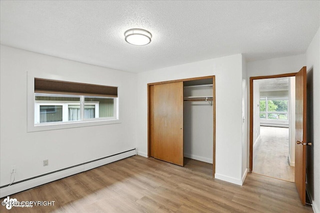 933 W 20th Ave, Anchorage, AK 99503 - unfurnished bedroom featuring a baseboard radiator, a textured ceiling, light wood-type flooring, and a closet