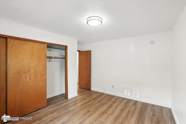 933 W 20th Ave, Anchorage, AK 99503 - unfurnished bedroom featuring light wood-type flooring, a closet, and a textured ceiling