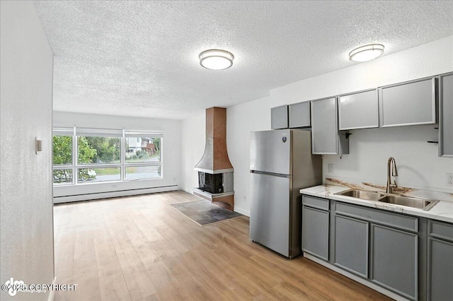 933 W 20th Ave, Anchorage, AK 99503 - kitchen with gray cabinetry, a textured ceiling, freestanding refrigerator, light countertops, and light wood finished floors