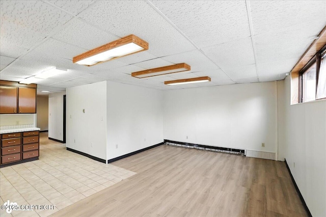 933 W 20th Ave, Anchorage, AK 99503 - unfurnished living room with light wood-style flooring, a paneled ceiling, and baseboard heating