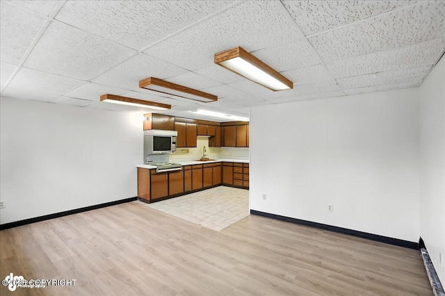 933 W 20th Ave, Anchorage, AK 99503 - kitchen with light countertops, brown cabinets, light wood finished floors, and a drop ceiling