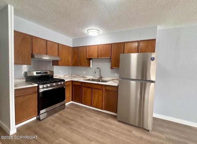 933 W 20th Ave, Anchorage, AK 99503 - kitchen with stainless steel appliances, light countertops, brown cabinetry, light wood finished floors, and a textured ceiling