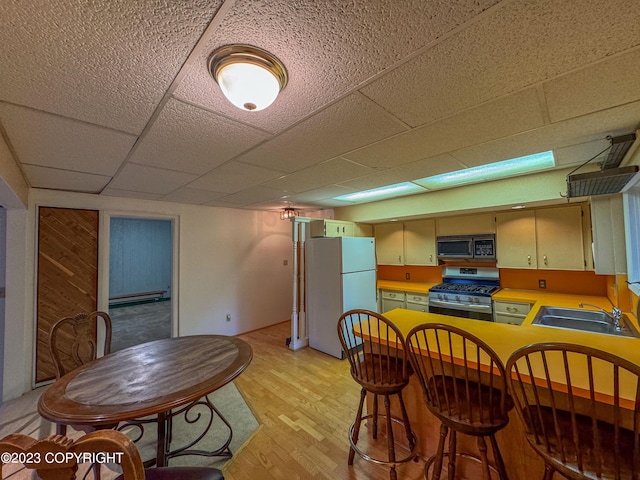 kitchen featuring gas range, black microwave, freestanding refrigerator, a sink, and light wood-type flooring