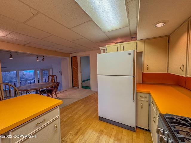 kitchen with freestanding refrigerator, range with gas stovetop, light countertops, light wood-style floors, and open floor plan