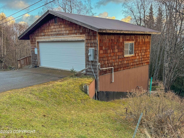view of property exterior featuring a garage, an outdoor structure, metal roof, and a yard