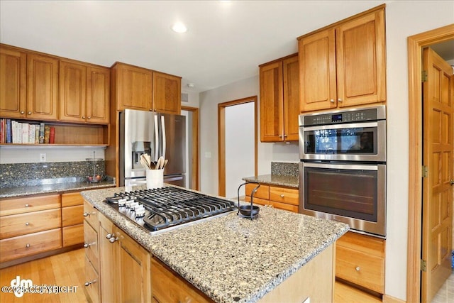 kitchen featuring stainless steel appliances, light stone counters, a center island, light wood-type flooring, and open shelves