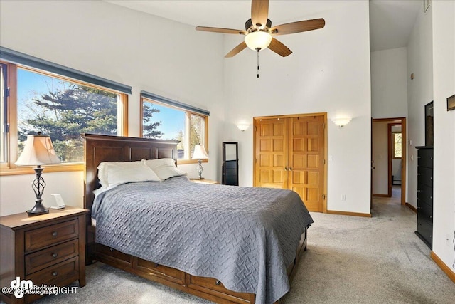bedroom with high vaulted ceiling, light carpet, multiple windows, baseboards, and a ceiling fan