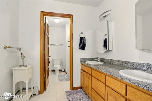 bathroom with tile patterned flooring, double vanity, toilet, and a baseboard heating unit