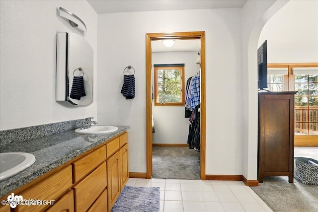 bathroom with healthy amount of natural light, baseboards, and double vanity