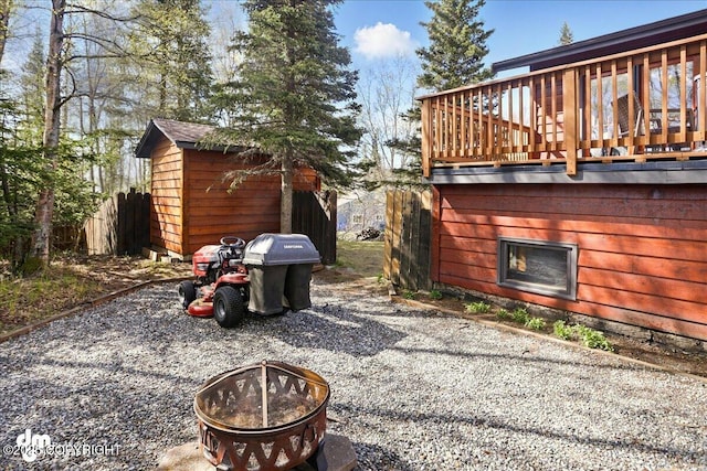 view of patio featuring an outdoor fire pit, a storage unit, an outdoor structure, and a wooden deck