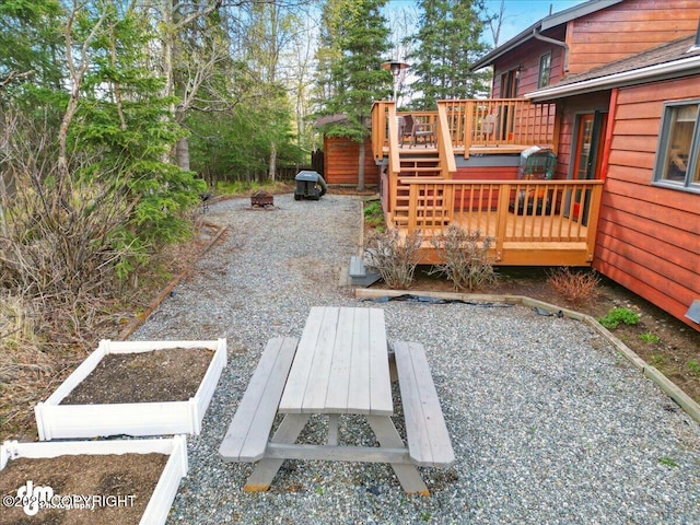 view of yard with a wooden deck, a fire pit, a patio, and a garden