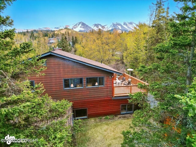 view of home's exterior with a wooded view and a deck with mountain view