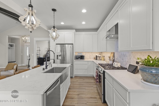 3589 N Magnolia Cir, Wasilla, AK 99654 - kitchen featuring stainless steel appliances, wall chimney range hood, a sink, a chandelier, and tasteful backsplash