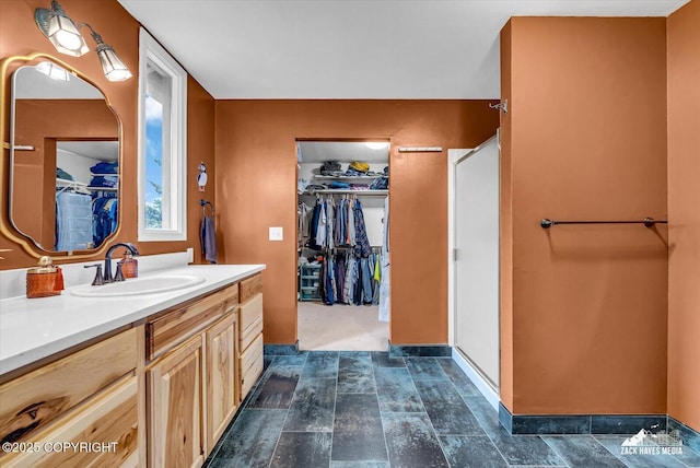 6010 Staedem Dr, Anchorage, AK 99504 - full bathroom featuring vanity, a walk in closet, baseboards, and stone finish flooring