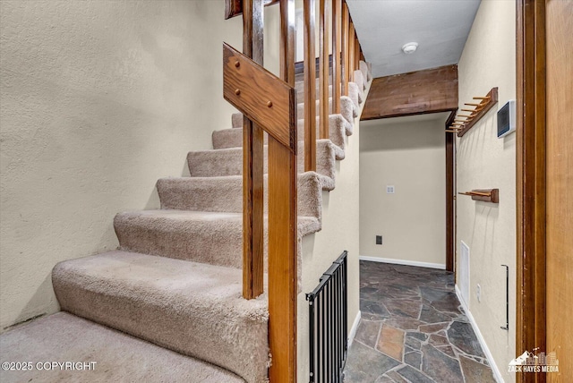 6010 Staedem Dr, Anchorage, AK 99504 - stairs featuring stone flooring, a textured wall, and baseboards
