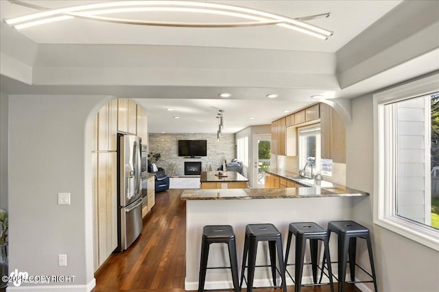 3833 Eastwind Dr, Anchorage, AK 99516 - kitchen featuring light brown cabinetry, a peninsula, stainless steel fridge, a kitchen bar, and dark wood-type flooring
