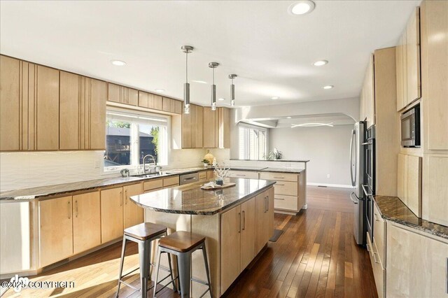 3833 Eastwind Dr, Anchorage, AK 99516 - kitchen with light brown cabinets, a peninsula, a sink, dark stone counters, and tasteful backsplash
