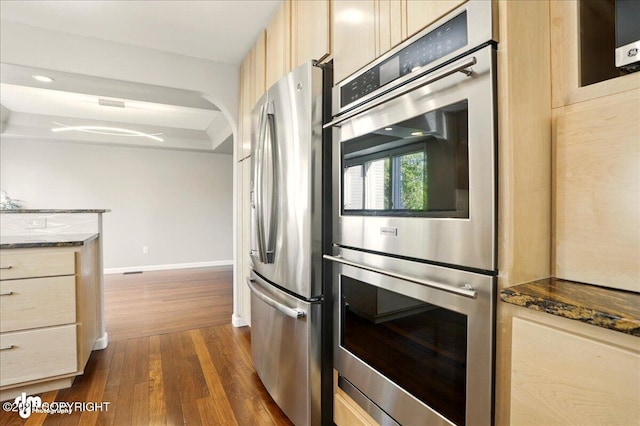 3833 Eastwind Dr, Anchorage, AK 99516 - kitchen with stainless steel appliances, dark wood-style floors, baseboards, dark stone counters, and light brown cabinetry