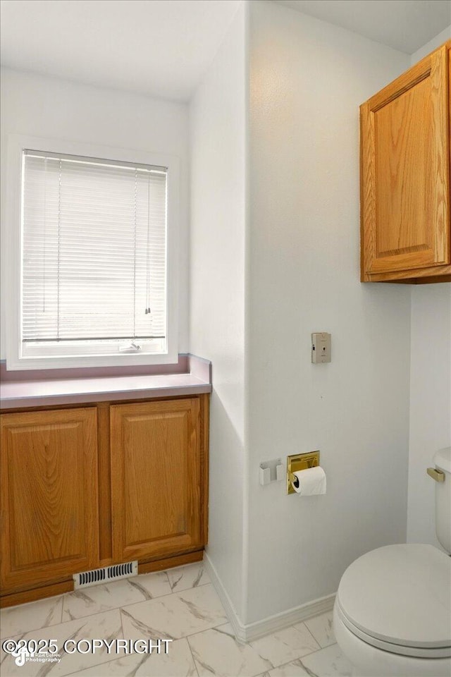 3833 Eastwind Dr, Anchorage, AK 99516 - bathroom with marble look tile flooring, toilet, and baseboards