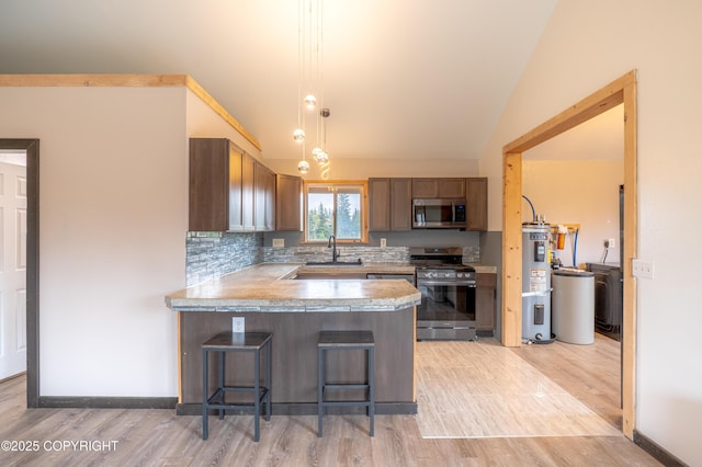 33533 Alder St, Anchor Point, AK 99556 - kitchen with appliances with stainless steel finishes, a breakfast bar, light countertops, a peninsula, and light wood-style floors